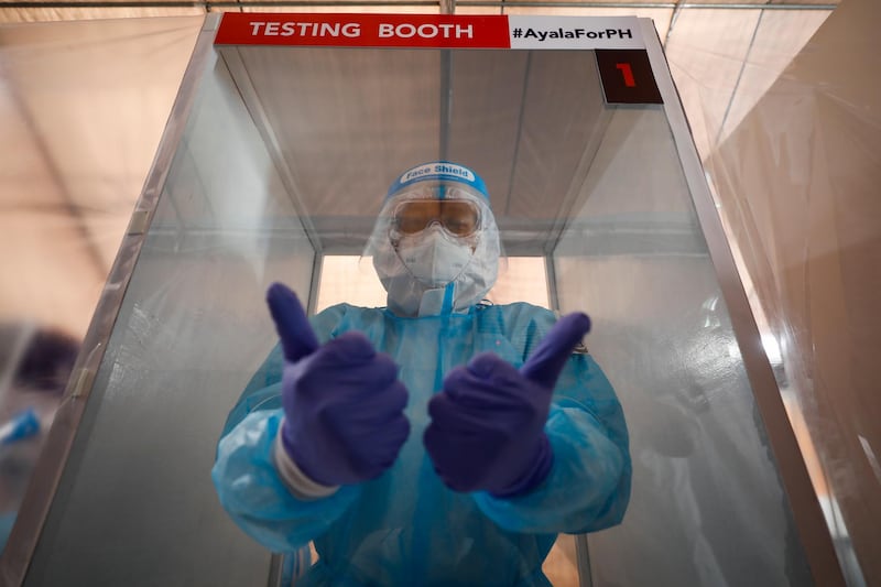 A health worker gestures inside a booth at a collection tent at the Philippine Sports Stadium, which is being used as a Covid-19 swab sample collection facility, in Bocaue, Bulacan province, Philippines. EPA