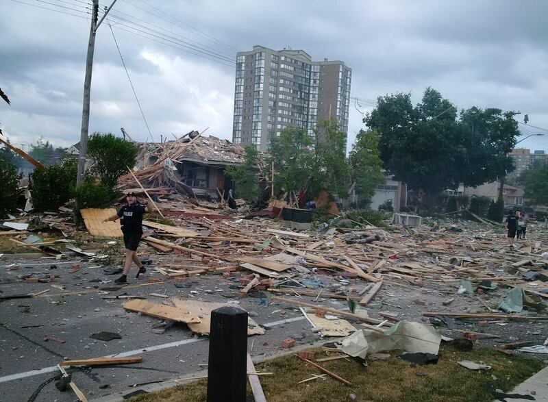 A police officer walks among debris littering a street after a house exploded in Mississauga, Ontario, on June 28, 2016. Police evacuated the area as they investigated the explosion. Zeljko Zidaric / The Canadian Press via AP