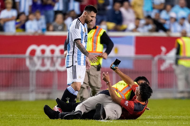 A fan is held down by security as he tries to take a picture of Argentina's Lionel Messi. AP