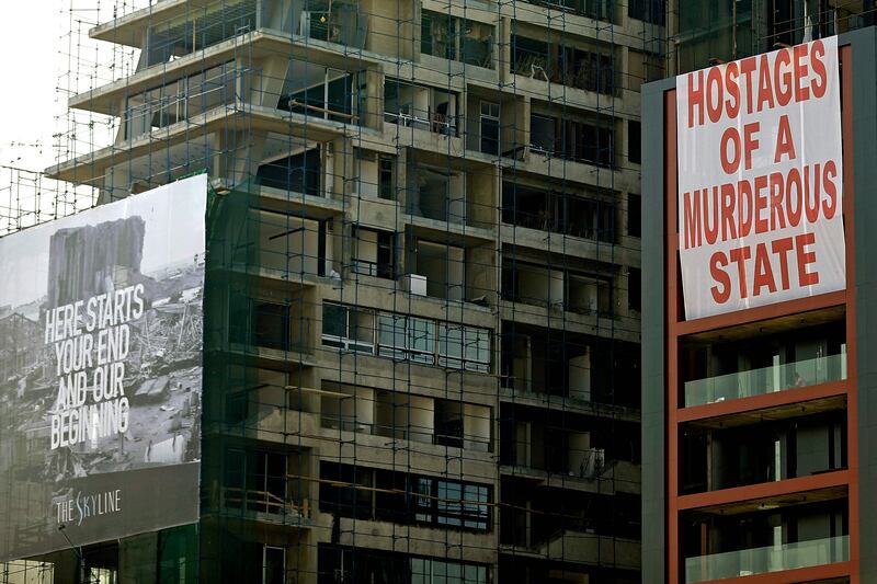 Banners reading 'Here starts your end and our beginning' and 'Hostages of a murderous state' hang on a building damaged in last August's port blast, as Lebanon marks a year since a the cataclysmic explosion devastated Lebanon's capital.