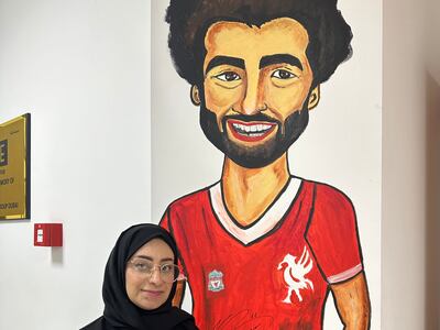Kawka Mohsen standing in front of her mural of Mohamed Sarah that is signed by him. Photo: Rana Afifi