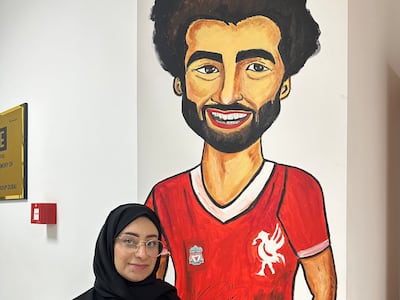 Kawka Mohsen standing in front of her mural of Mohamed Sarah that is signed by him. Photo: Rana Afifi