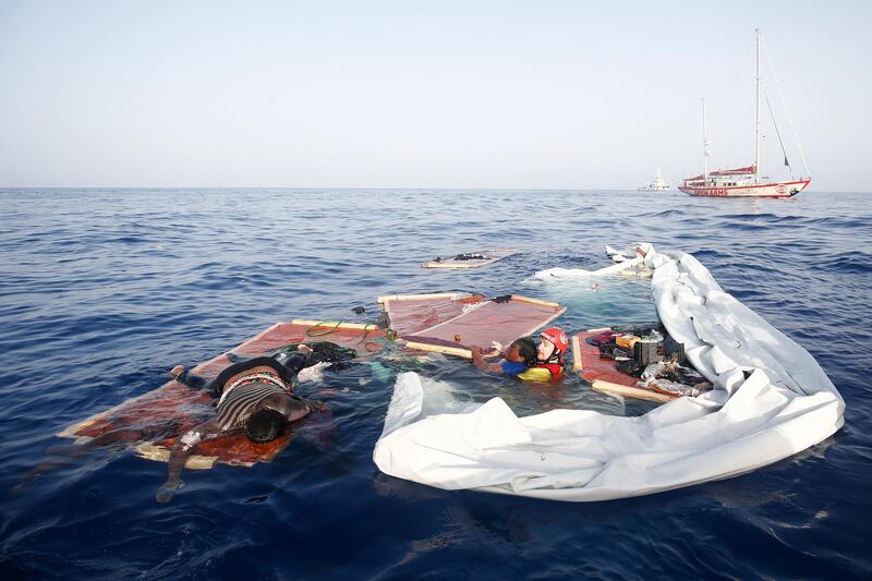 EDITORS NOTE: Graphic content / -- AFP PICTURES OF THE YEAR 2018 --

A member of the Spanish NGO Proactiva Open Arms rescues a woman (Cameroonian Josepha, 40-years-old) from a sinking boat as another lies dead on what is left of the deck in the Mediterranean Sea about 85 miles off the Libyan coast on July 17, 2018.  / AFP / PAU BARRENA
