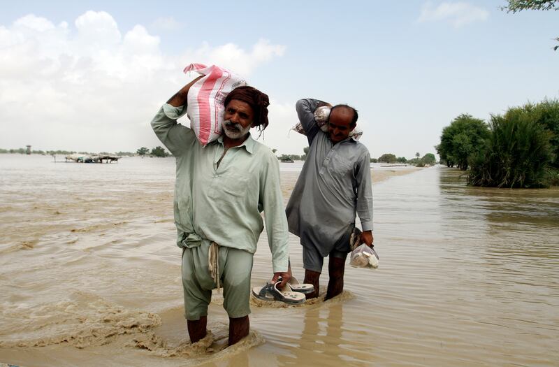 Displaced people carrying food aid wade through floodwaters in Rajanpur, Punjab province. Flooding has caused more than $10 billion in damage across Pakistan. AP