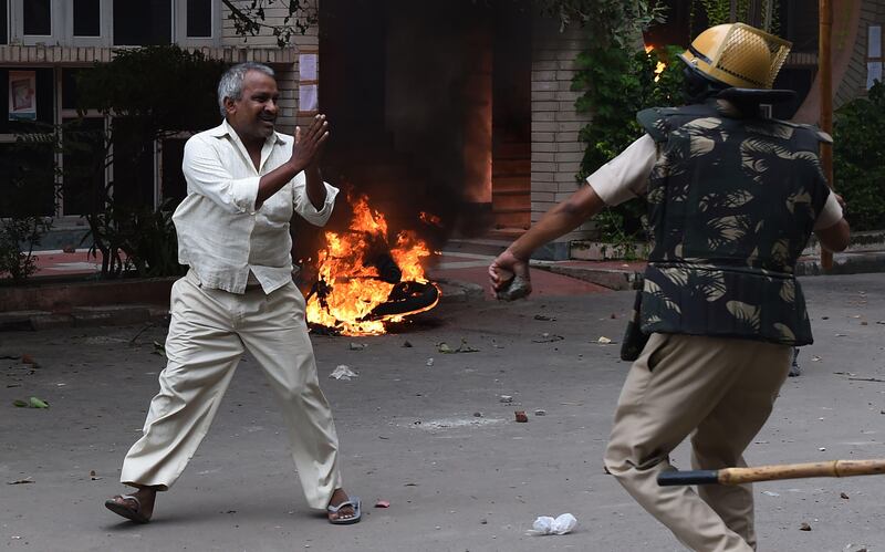 A follower of Indian religious leader Gurmeet Ram Rahim Singh pleads for his safety after being hit with a stick during clashes between  followers and security forces in Panchkula. Money Sharma / AFP Photo