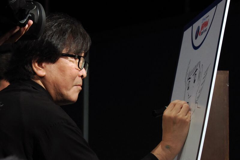 Yoichi Takahashi, Japanese manga artist known for his work of ‘Captain Tsubasa’, draws an illustration during a reception party for French football team Paris Saint-Germain at a Tokyo hotel. AFP