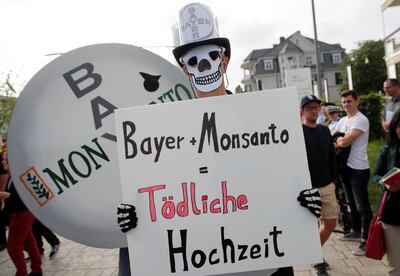 FILE PHOTO: People protest against the merger of Germany's pharmaceutical and chemical maker Bayer with U.S. seeds and agrochemicals company Monsanto, before Bayer's annual general shareholders meeting in Bonn, Germany, May 25, 2018. A placard reads: " Bayer + Monsanto = deadly marriage". REUTERS/Wolfgang Rattay/File Photo