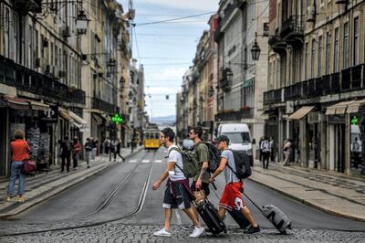 Tourist cross a street in downtown Lisbon on June 18, 2021. - The Portuguese government will limit travel to and from the greater Lisbon area during the weekend following an increase in coronavirus cases in the region. (Photo by PATRICIA DE MELO MOREIRA / AFP)