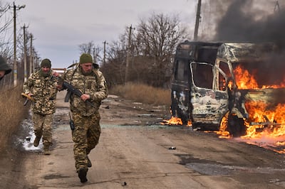 Ukrainian soldiers pass a burning volunteer bus after a Russian drone hit it near Bakhmut, Ukraine, in 2023. AP