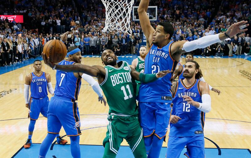 Boston Celtics guard Kyrie Irving shoots between Oklahoma City Thunder forward Carmelo Anthony and guard Andre Roberson in the second quarter of an NBA basketball game in Oklahoma City. Sue Ogrocki / AP Photo