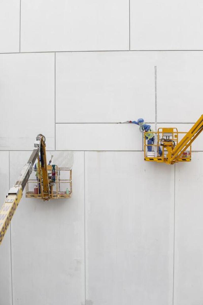 Labourers repair minor imperfections to the ultra-high performance fibre reinforced concrete panels that form the cladding of the Louvre Abu Dhabi. Antoine Robertson / The National