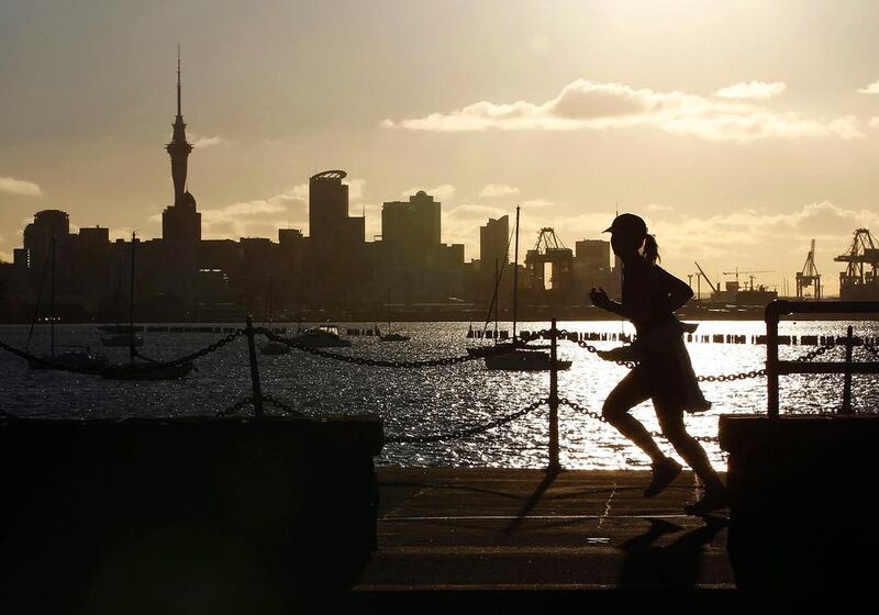 A jogger runs along the seawall in Auckland, with the city skyline in the background. Reuters