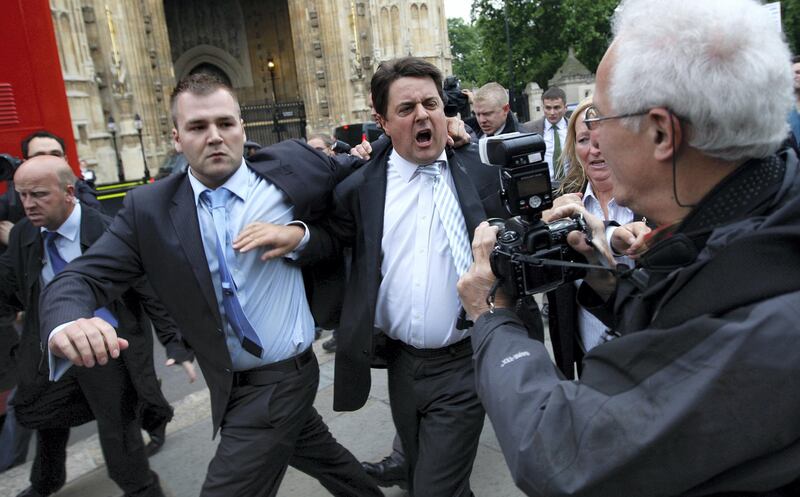 British National Party (BNP) leader Nick Griffin (C) leaves a news conference after it was disrupted by protestors, outside of the Houses of Parliament in London June 9, 2009. Scores of protesters shouting "Nazi scum, off our streets" broke up a news conference held by the far-right British National Party's two European deputies outside parliament on Tuesday.     REUTERS/Stephen Hird      (BRITAIN POLITICS IMAGES OF THE DAY CONFLICT) - GM1E5691PND01