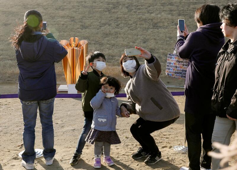A family takes a selfie with the Olympic flame on a cauldron displayed at Ishinomaki Minamihama Tsunami Recovery Memorial Park. EPA