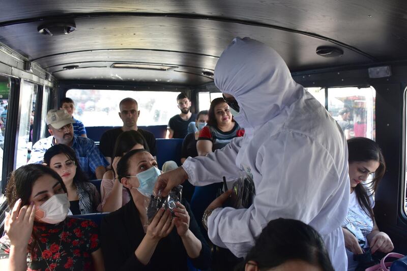 Syrian volunteers distribute face masks to passengers on a government bus as part of precautionary measures to prevent the spread of the coronavirus in Damascus.  EPA