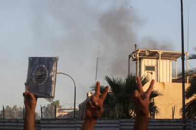 A protester holds up a Quran as smoke rises from the Swedish embassy building. Reuters