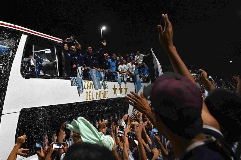 Argentina players on an open-top bus are greeeted by supporters at the airport as they celebrate winning the 2022 World Cup. AFP