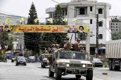 Lebanese army vehicles drive past a banner for the Lebanese Shiite Muslim movement Hezbollah with text in Arabic reading "the flag will not fall", in the southern city of Nabatiyeh, on May 15, 2022. AFP