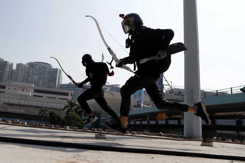 Protesters race with bows as they practise running away from riot police, on the roof of a bus shelter near the Cross Harbour Tunnel, which was blocked after demonstrators occupied the nearby Hong Kong Polytechnic University. Reuters