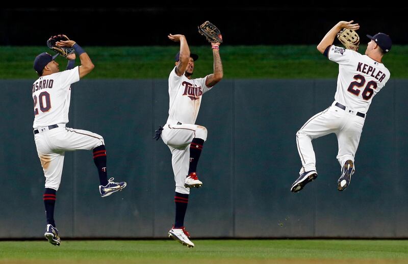 Three Minnesota Twins outfielders (from left, Eddie Rosario, Byron Buxton and Max Kepler) mime shooting basketballs as they celebrate their team's 6-0 win over the Detroit Tigers in a baseball game in Minneapolis. Jim Mone / AP Photo