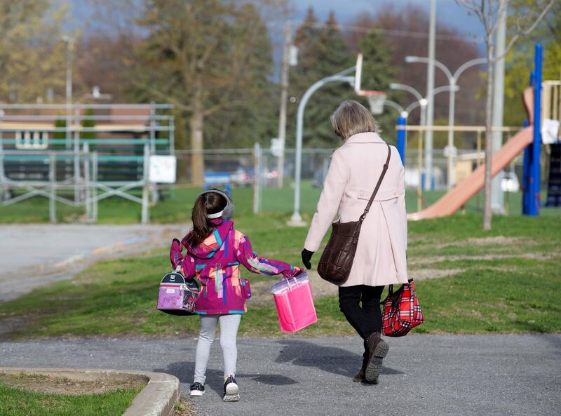 A pupil escorted into the schoolyard by a teacher as schools outside the greater Montreal region begin to reopen, Saint-Jean-sur-Richelieu, Quebec, Canada, May 11. Christinne Muschi / Reuters