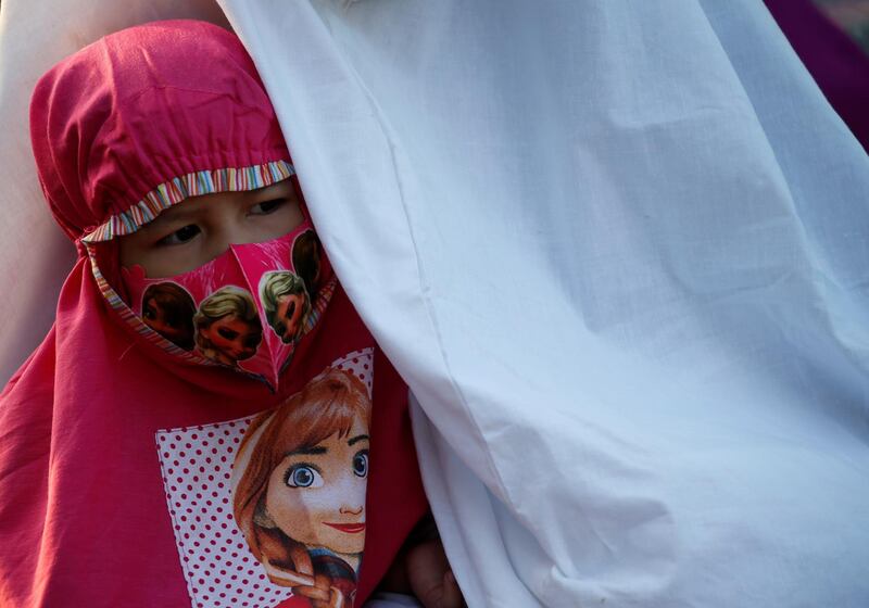 A face mask-wearing girl attends Eid Al Adha prayers on the street in Jakarta. Reuters
