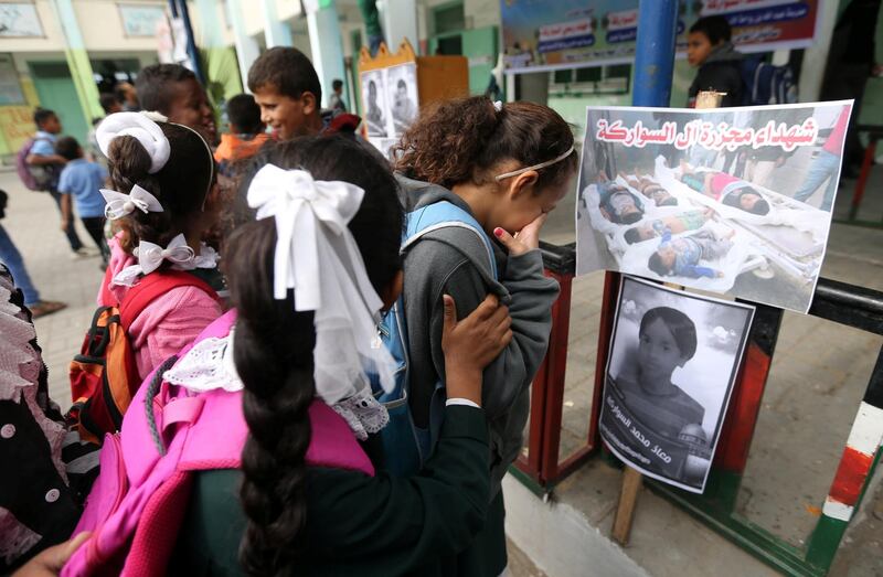 Colleagues of Palestinian schoolchildren of Abu Malhous family, who were killed in Gaza, react as they look at their pictures at their school in the central Gaza Strip. Reuters