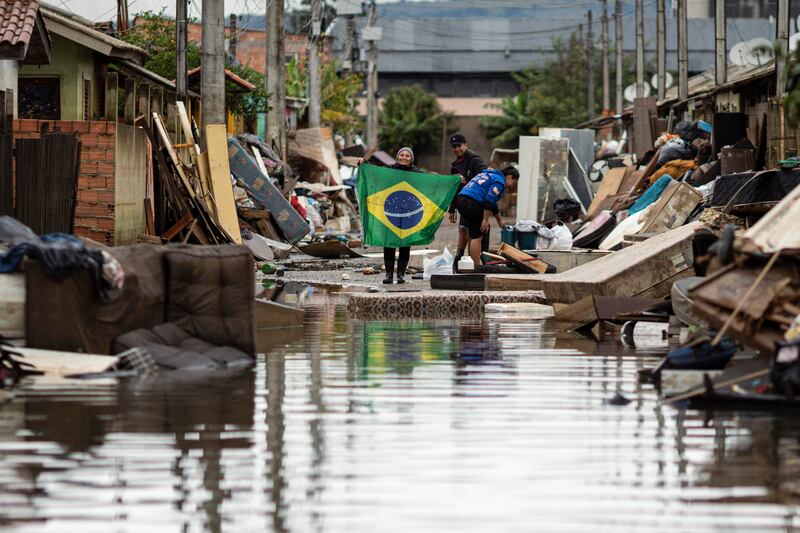 A woman holds a Brazilian flag in the middle of a flooded street in Porto Alegre, Brazil. EPA