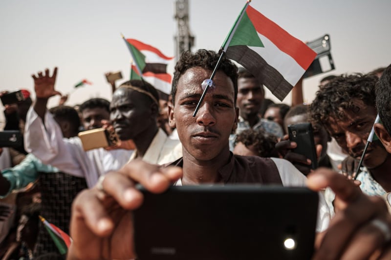 (FILES) In this file photo taken on June 22, 2019 A man poses for a "selfie" photo with a cell phone as he awaits the arrival of the deputy head of Sudan's ruling Transitional Military Council (TMC) and commander of the Rapid Support Forces (RSF) paramilitaries, during a rally in the village of Abraq, about 60 kilometers northwest of Khartoum.  / AFP / Yasuyoshi CHIBA
