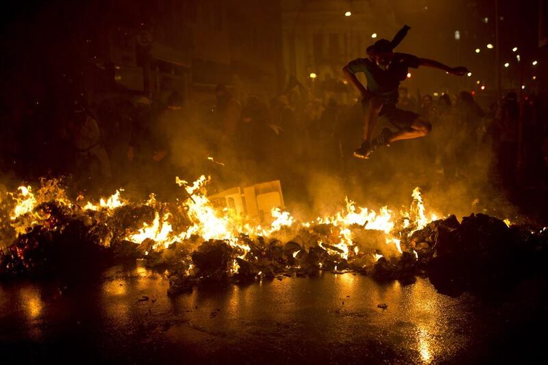 A demonstrator with his face covered jumps over a burning barricade during a march in support of teachers on strike in Rio de Janeiro. Felipe Dana / AP 