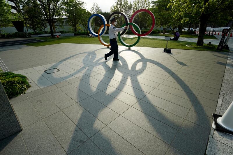 A security guard walks past the Olympic rings in Tokyo, Japan. The city is due to host the Olympic Games this summer, after they were postponed last year due to Covid-19. AP Photo