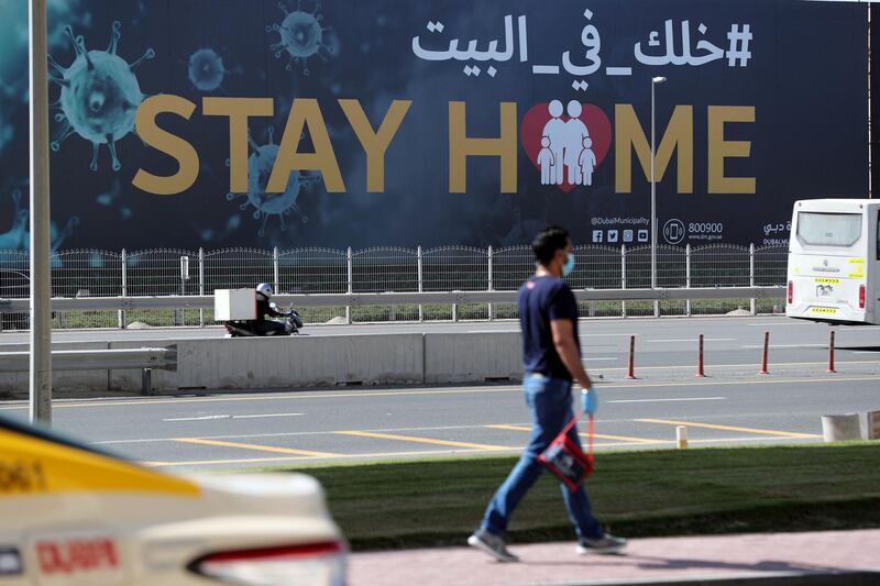 Dubai, United Arab Emirates - Reporter: N/A: Coronavirus/Covid-19. A man walks passed a huge sign on Sheikh Zayed Road that says 'Stay Home'. Tuesday, May 5th, 2020. Dubai. Chris Whiteoak / The National