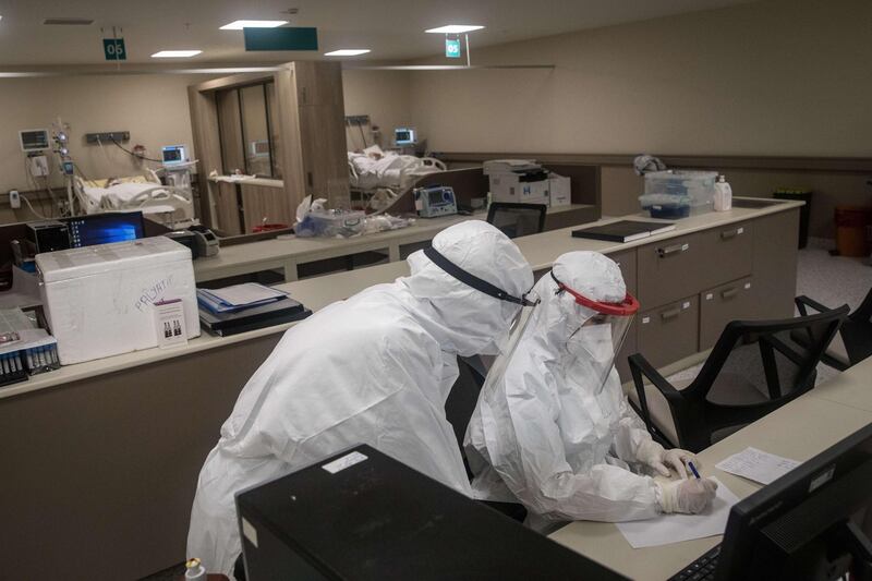 Medical workers dressed in personal protective equipment write patient reports inside a Covid-19 ICU unit at the Kartal Dr Lutii Kirdar Education and Research Hospital in Istanbul. Getty Images/AFP