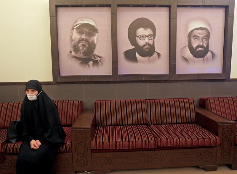 A picture taken during a guided tour organised by the Lebanese Shiite movement Hezbollah shows a mask-clad woman sitting next to portraits of late Hezbollah leader Abbas Mussawi(C), late commanders Imad Mughnieh (L) and Ragheb Harb, at a centre in Beirut's southern suburbs on March 31, 2020. / AFP / -
