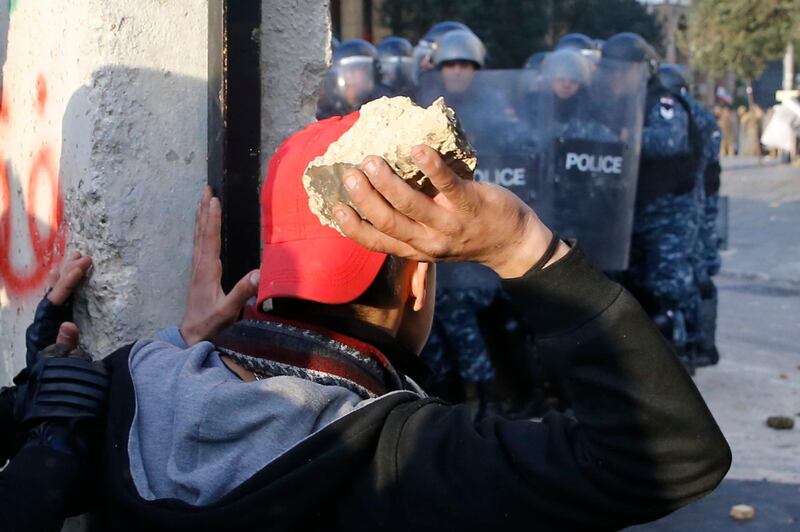 Anti-government demonstrators prepare to throw stones toward riot police at a road leading to the parliament building, during a protest against a parliament session to vote of confidence for the new government, in downtown Beirut, Lebanon. AP Photo