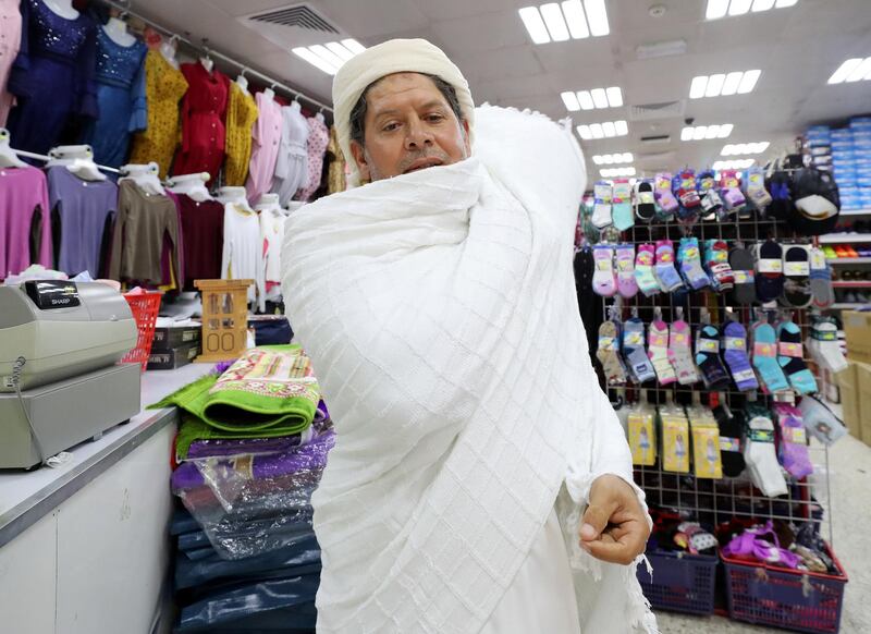Abu Dhabi, United Arab Emirates - July 30, 2019: Mohammed Barakat 45, from Egypt shows us a Ihram which is worn on Hajj at Salmin Trading Shops. Monday the 30th of July 2019. Downtown, Abu Dhabi. Chris Whiteoak / The National