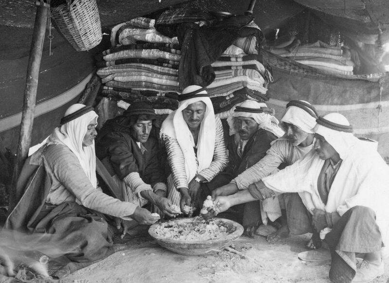 circa 1920:  A group of men eat out of a communal dish in a tent in Jericho, West Bank.  (Photo by Chalil Raad/Three Lions/Getty Images)