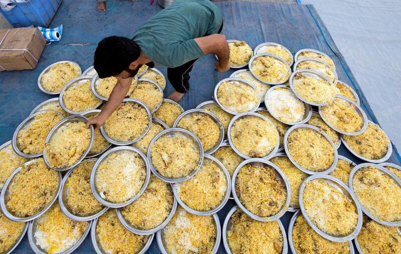 DUBAI, UNITED ARAB EMIRATES -  A volunteer arranging plates of biryani to be served to the workers.  Dubai Police join hands with Berkeley Assets to serve up Iftar dinner to mark Laylatul Qadr for 10,000 labourers with seating for 5,000 and another 5,000 laborers will go home with meal boxes in Al Muhaisnah, Dubai.  Ruel Pableo for The National