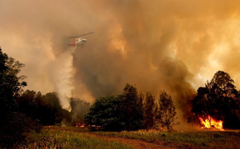 A fire bombing helicopter works to contain a bushfire along Old Bar road in Old Bar, New South Wales, Australia. REUTERS