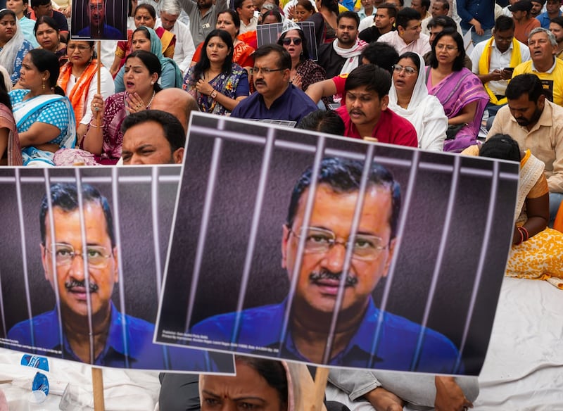 Aam Aadmi Party supporters hold up photos of leader and Delhi Chief Minister Arvind Kejriwal during a protest in India's capital. Bloomberg
