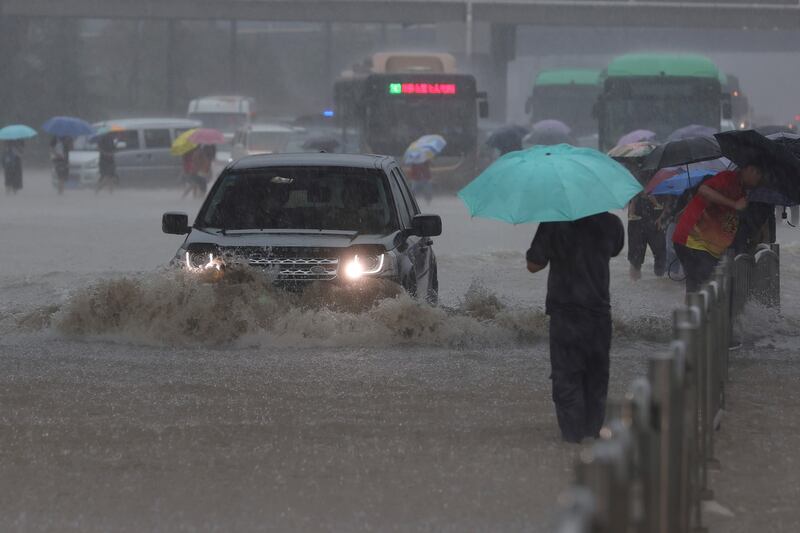 Traffic struggles through flooding in Zhengzhou, the capital of China's central Henan province.   The banks of rivers are reported to have burst, leaving people in waist-high water.