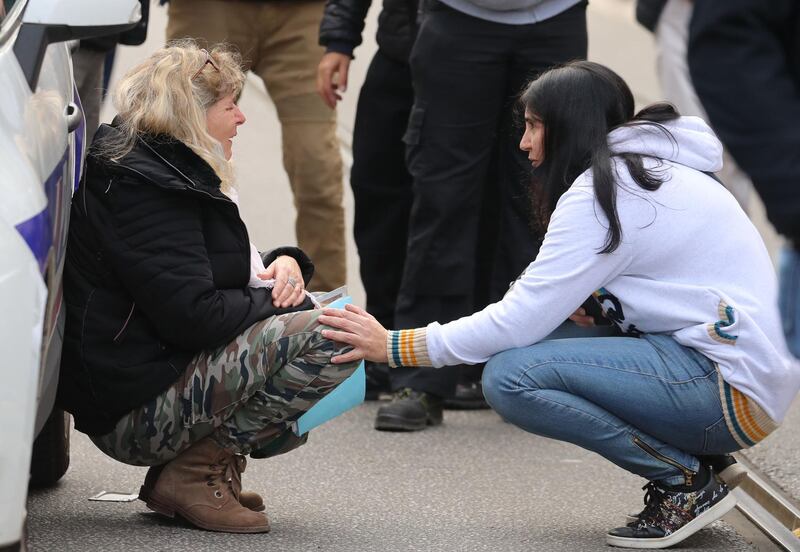 A woman kneels by a police car as she cries in Nice. AFP