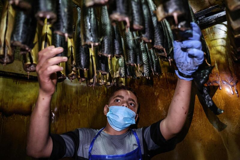 A Palestinian man smokes mackerels at a fish market before the Eid Al Fitr holiday, in Rafah, in southern Gaza Strip. AFP