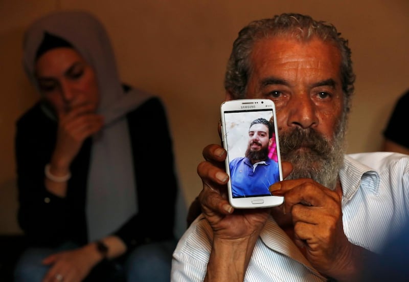 Khaldoun Mohammed, 58, shows a portrait of his son Mohammed, 27, who is still missing at sea while he was trying with other migrants to reach Cyprus on a boat, as he sits at his house in Tripoli, north Lebanon. AP Photo
