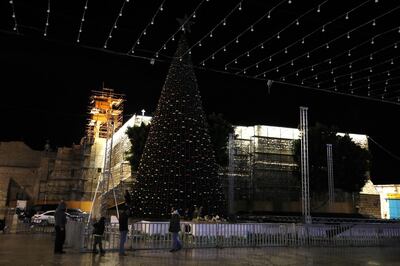 epa06372845 Palestinians stand in front of the Christmas tree near the church of nativity in the west bank city of bethlehem 06 December 2017. The christian Palestinians turned off the tree lights as a protest against US President Donald J. Trump declaration recognizing Jerusalem as the capital of the Israel.  EPA/ABED AL HASHLAMOUN