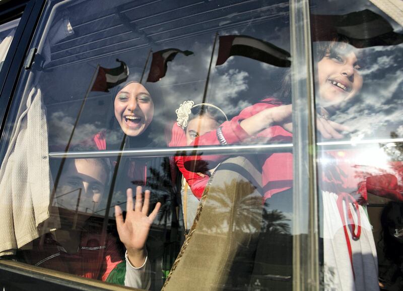 ABU DHABI, UNITED ARAB EMIRATES, Nov. 27, 2013:   
Young girls, students from Dar al Uloom Private School in Abu Dhabi, bunch up at their bus window to pose for a photograph on Wednesday, Nov. 27, 2013, after their performance at the Abu Dhabi University in Abu Dhabi, at the occasion of early celebrations of the 42nd UAE NAtional Day. (Silvia Razgova / The National)

Section: National
Reporter: Roberta Pennington
Publishing: Nov. 28, 2013 *** Local Caption ***  sr-131127-natdaycelebration0486.jpg