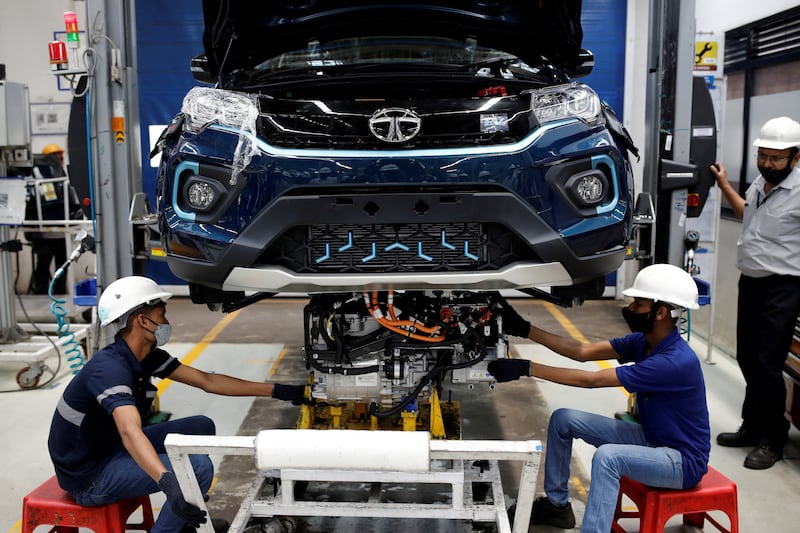 Workers install an electric motor inside a Tata Nexon electric SUV at a Tata Motors plant in Pune. Reuters