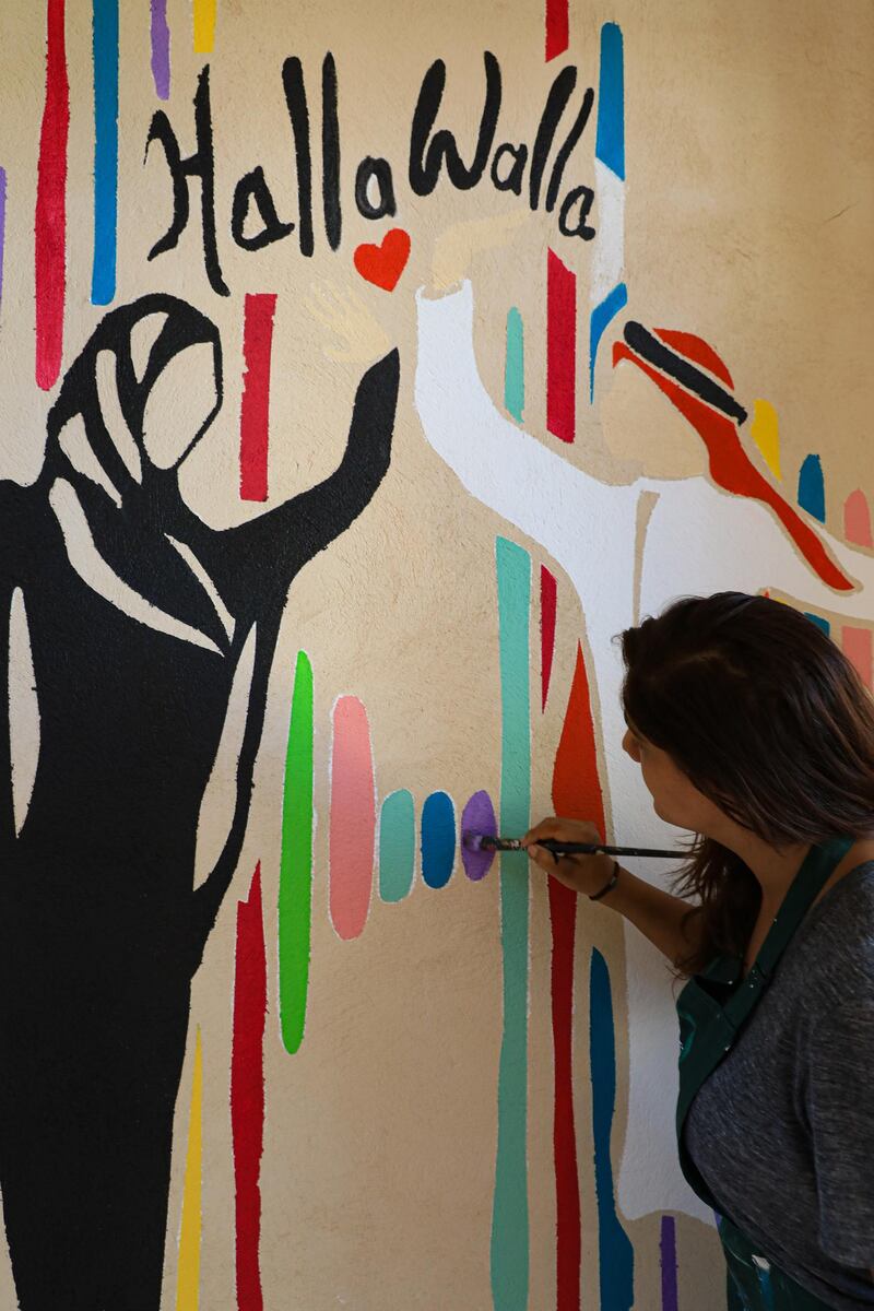 Amrita Sethi working on one of her murals 'Halla Walla', which shows a high-five greeting between an Emirati man and woman