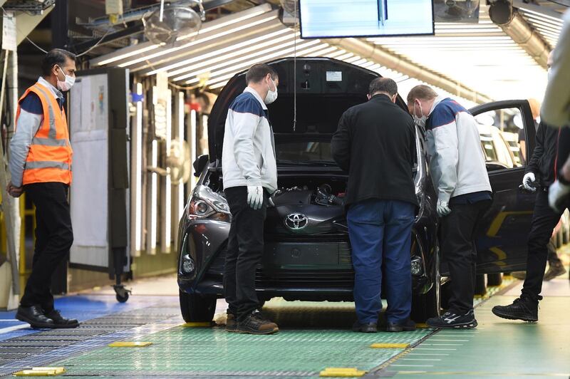 Employees of Toyota, wear protective facemasks and gloves as they work on vehicles at the assembly line of the Toyota automobile plant in Onnaing, near Valenciennes, on April 23, 2020, as the factory reopened after more than a month break aimed at curbing the spread of the COVID-19 (novel coronavirus).  / AFP / FRANCOIS LO PRESTI
