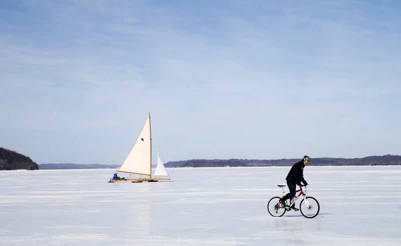 An antique ice boat sails behind a cyclist across the frozen Hudson river. (Mike Segar / Reuters / March 7, 2014)